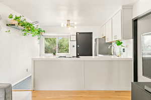 Kitchen featuring a chandelier, light hardwood floors, gas cooktop, and quartz countertops