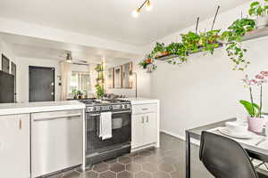 Kitchen featuring gas range oven, dishwasher, white cabinets, and quartz countertops