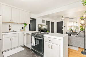 Kitchen featuring appliances with stainless steel finishes, open floor plan, a sink, a peninsula, and quartz countertops