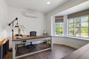 Office space featuring a wall mounted AC, ornamental molding, wood finished floors, and baseboards