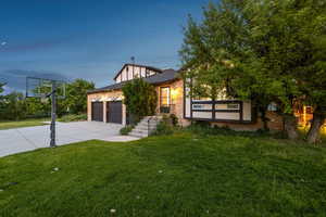 View of front of property featuring driveway, a garage, brick siding, and a front yard