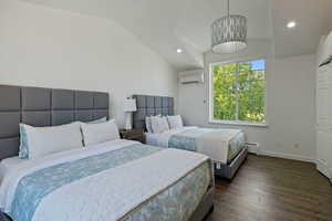 Bedroom with baseboard heating, a wall unit AC, vaulted ceiling, and dark wood-style floors