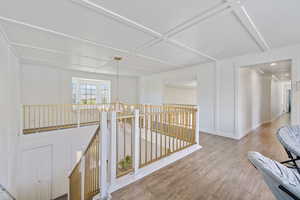 Hall with an upstairs landing, wood finished floors, and baseboards