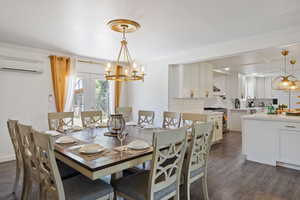 Dining space with a wall mounted AC, dark wood-type flooring, a chandelier, and ornamental molding