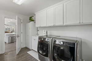 Laundry area with washer and clothes dryer, visible vents, dark wood finished floors, cabinet space, and a wealth of natural light