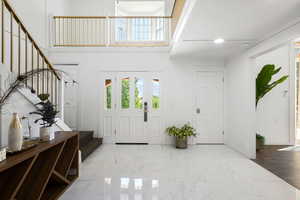 Foyer entrance with baseboards, stairs, a high ceiling, and a wealth of natural light