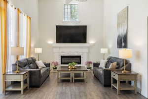 Living room featuring a towering ceiling, wood finished floors, and a glass covered fireplace