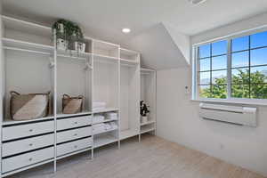 Walk in closet with visible vents, a wall mounted AC, and wood finished floors