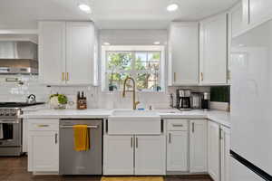 Kitchen with a sink, wall chimney exhaust hood, backsplash, and stainless steel appliances