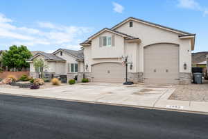 View of front of home with stone siding, fence, stucco siding, and driveway