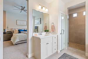 Ensuite bathroom featuring a ceiling fan, a tile shower, and vanity