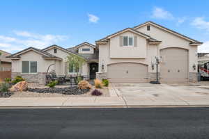 View of front facade with stone siding, stucco siding, concrete driveway, fence, and a tiled roof