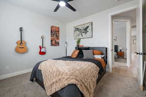Bedroom featuring light colored carpet, baseboards, and ceiling fan