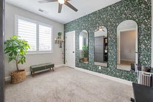 Living area featuring wallpapered walls, a ceiling fan, carpet flooring, baseboards, and arched walkways