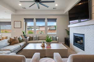 Carpeted living room featuring a ceiling fan, a fireplace, and recessed lighting