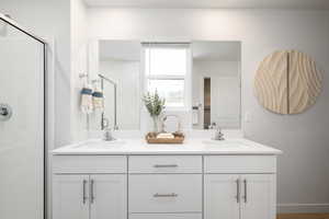 Bathroom featuring a stall shower and double vanity
