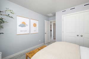 Bedroom featuring light colored carpet, baseboards, a closet, and a textured ceiling