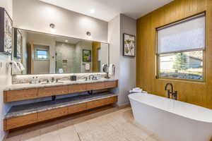 Full bathroom with a shower stall, a freestanding bath, double vanity, tile patterned flooring, and baseboards