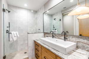 Bathroom featuring tile walls, a shower stall, and vanity