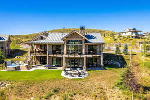 Rear view of property with a standing seam roof, a chimney, a patio area, stairway, and metal roof