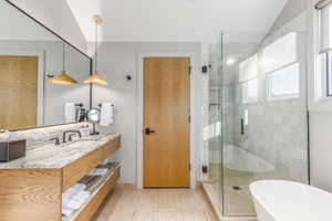 Full bath with a stall shower, vanity, a freestanding tub, lofted ceiling, and tile patterned flooring