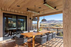 Wooden deck featuring a mountain view, ceiling fan, and outdoor dining area