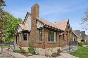 Exterior space with a gate, a chimney, fence, a front yard, and brick siding