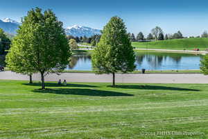 View of community featuring a water and mountain view and a lawn