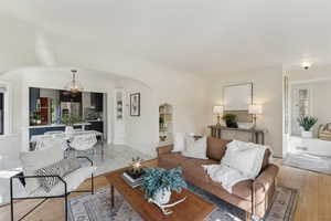 Living room featuring an inviting chandelier, visible vents, baseboards, and arched walkways