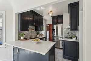 Kitchen featuring a peninsula, a sink, under cabinet range hood, appliances with stainless steel finishes, and tasteful backsplash