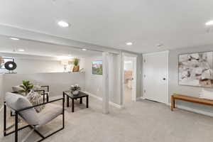Living area featuring light carpet, baseboards, visible vents, and recessed lighting