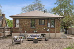 Rear view of property featuring central air condition unit, fence, an outdoor living space with a fire pit, and brick siding