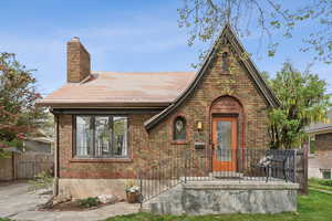 Tudor house with a chimney, brick siding, and fence