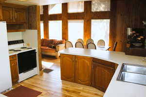 Kitchen with white appliances, light countertops, a sink, and light wood-style flooring