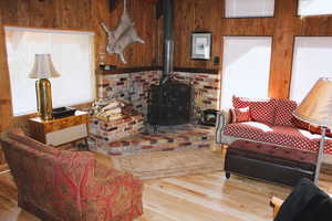 Living room with wood walls, hardwood / wood-style floors, and a wood stove