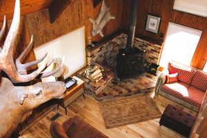 Living room featuring wood walls, a wood stove, and wood finished floors