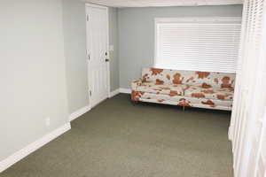 Unfurnished room featuring dark colored carpet and baseboards