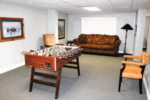 Rec room featuring carpet floors, a paneled ceiling, and baseboards