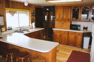 Kitchen featuring black microwave, a sink, a kitchen breakfast bar, and light countertops