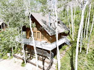 Back of property with a shingled roof, a deck, and stairs