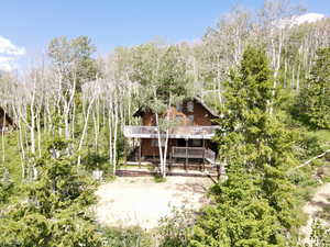 View of front of house featuring stairway, a view of trees, and a deck