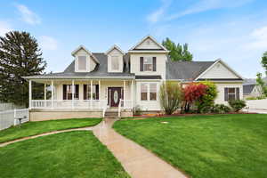 View of front of property featuring covered porch, roof with shingles, fence, and a front lawn