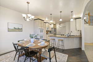 Dining area featuring an inviting chandelier, arched walkways, and baseboards
