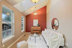 Carpeted living area featuring lofted ceiling, a wealth of natural light, and baseboards