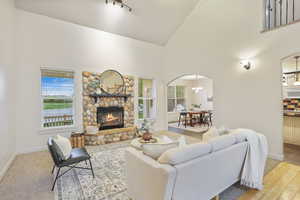 Living room with arched walkways, baseboards, a healthy amount of sunlight, and high vaulted ceiling