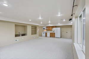Unfurnished living room with a sink, light colored carpet, visible vents, and recessed lighting