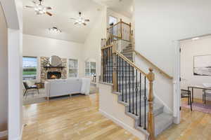 Staircase with a ceiling fan, baseboards, high vaulted ceiling, hardwood / wood-style flooring, and a fireplace