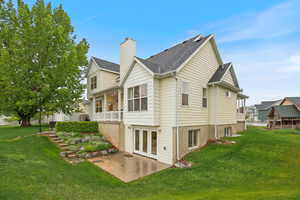 Back of property featuring a patio, roof with shingles, a chimney, and a lawn