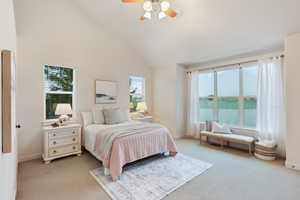 Primary bedroom featuring light colored carpet, baseboards, and high vaulted ceiling