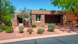 Southwest-style home featuring concrete driveway, stone siding, stucco siding, and an attached garage